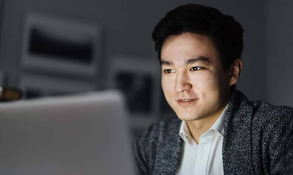 A young professional graduate in suit using a laptop