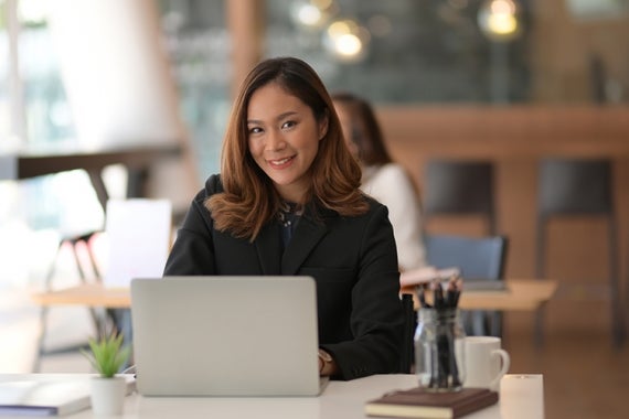 A professional women using her laptop and looking at the camera